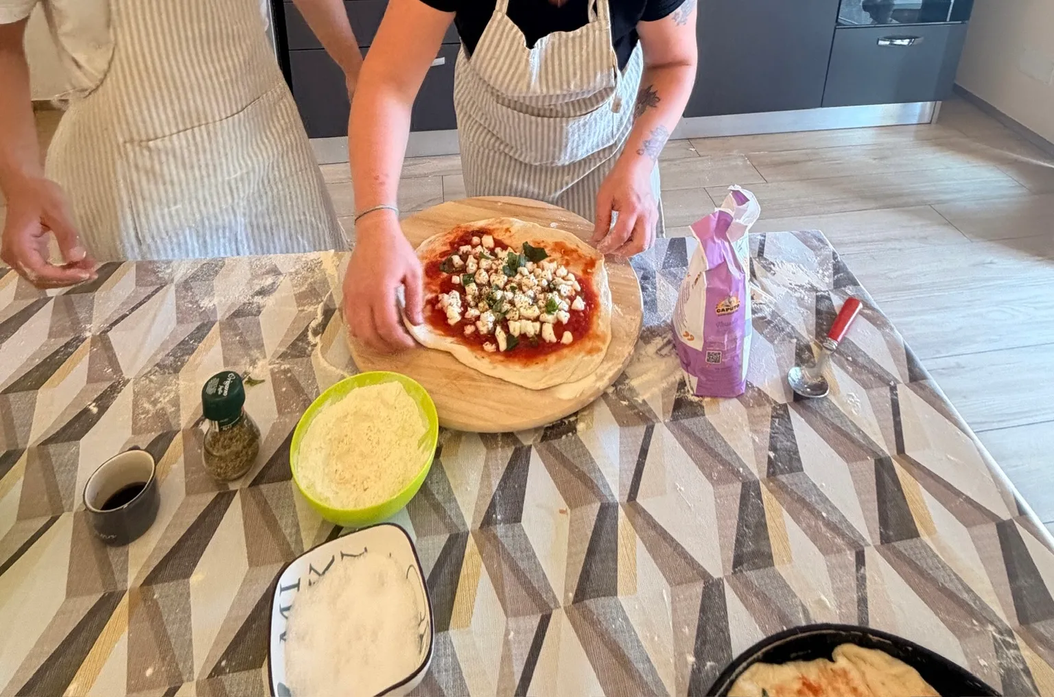 A freshly topped margherita pizza on a wooden peel at a pizza making class near Cagliari.
